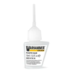 Photographie en gros plan sur un fond blanc neutre d'un flacon de Colle Plastique - Warhammer Colour. Le flacon en plastique blanc semi-translucide présente une forme géométrique asymétrique avec un côté biseauté, et il est surmonté d'un long capuchon applicateur très fin et pointu de couleur blanche. L'étiquette blanche frontale affiche de manière très lisible le logo officiel noir "WARHAMMER", souligné par le mot "COLOUR" inscrit en lettres noires dans un rectangle jaune vif. Sous ce bloc de marque, on peut lire les mentions textuelles "PLASTIC GLUE", la contenance de "15ml / 0.5 fl. oz" accompagnée du symbole d'estimation, l'inscription "MADE IN THE UK", ainsi que plusieurs lignes de mentions légales et d'adresses écrites en petits caractères noirs.