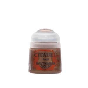 Photographie de face sur un fond blanc uni d'un pot de peinture en plastique transparent de la marque Citadel. Le flacon laisse transparaître une peinture acrylique métallique de couleur or cuivré foncé aux reflets chauds, surmontée d'un capuchon hermétique en plastique blanc translucide. L'étiquette centrale affiche un fond rouge vif texturé évoquant un blason entouré d'éclaboussures. Les inscriptions imprimées en lettres capitales noires indiquent de haut en bas la marque "CITADEL", la catégorie de gamme "BASE" et le nom spécifique de la teinte pour ce pot de Base: Balthasar Gold.