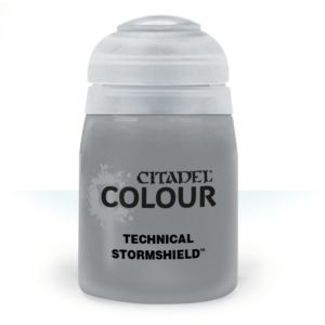 Une photographie de studio présentant un pot de peinture Citadel Colour de la gamme Technical. Le flacon transparent laisse apparaître un liquide gris clair opaque. L'étiquette blanche affiche les logos "Citadel Colour" en noir et la dénomination du produit "Technical: Stormshield" en lettres capitales grasses. Le capuchon en plastique blanc translucide est doté du système d'ouverture à charnière typique de la marque. L'ensemble est présenté sur un fond blanc épuré avec un léger reflet à la base du pot.