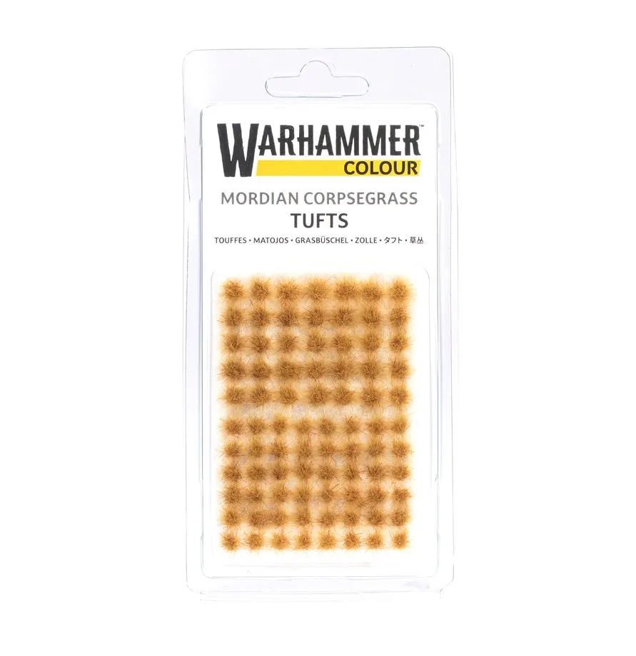Photographie de studio présentant un pack de Touffes Mordian Corpsegrass WHC sous blister transparent. On y voit une grille de petites herbes synthétiques d'un brun sableux et aride sur un support blanc. L'emballage affiche clairement la marque Citadel Colour avec son logo jaune distinctif, garantissant un accessoire de finition de haute qualité pour les décors de modélisme.