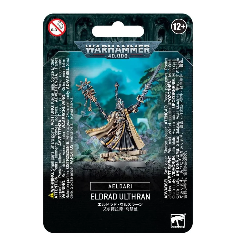 Emballage sous blister officiel d'une figurine de personnage pour le jeu de stratégie Warhammer 40,000, présenté de face avec une fente d'accroche au sommet. Le grand logo argenté de Warhammer 40,000 est centré en haut, incrusté sur une bordure supérieure gris foncé sculptée de reliefs de visages hurlants. L'illustration centrale met en scène Eldrad Ulthran, le plus puissant et légendaire Grand Prophète de la faction Aeldari. Le personnage arbore une armure baroque noire et dorée très détaillée, de longues robes noires, et une grande cape beige à doublure bordeaux ornée de runes dorées. Il porte un casque conique noir et doré à lentilles turquoise et se tient debout sur des ruines de pierre. De sa main droite, il brandit son grand bâton runique d'Ulthamar surmonté d'une icône géométrique complexe, tandis que sa main gauche tient une lame de sorcière argentée et turquoise pointée vers l'arrière. L'arrière-plan mystique est baigné d'une lueur turquoise. La partie inférieure noire comporte de grands encadrés textuels traduisant le nom du personnage en plusieurs langues, dont la mention blanche "AELDARI" et "ELDRAD ULTHRAN" juste en dessous. Les logos d'avertissement de sécurité pour les enfants et d'âge recommandé "12+" encadrent le haut, tandis que le logo blanc officiel de Warhammer Citadel figure dans le coin inférieur droit.