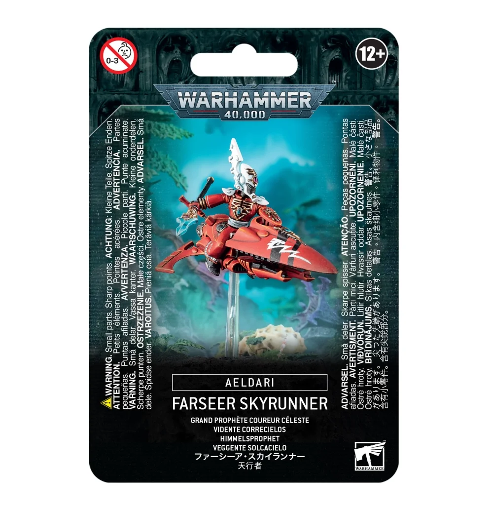 Emballage sous blister officiel d'une figurine de personnage pour le jeu de stratégie Warhammer 40,000, présenté de face avec un système d'accroche au sommet. Le grand logo argenté de Warhammer 40,000 est centré en haut, incrusté sur une bordure supérieure gris foncé sculptée de reliefs de visages hurlants. L'illustration centrale met en scène le Grand Prophète Coureur Céleste (indiqué en anglais Farseer Skyrunner), un puissant sorcier extraterrestre de la faction Aeldari. Le personnage est vêtu d'une armure rouge vif, porte un casque conique blanc orné d'une rune, et pilote une moto-jet profilée aérodynamique de couleur rouge avec des bandes noires et des lignes blanches sur le nez. Le véhicule lévite sur une tige transparente au-dessus d'un sol rocheux, devant un arrière-plan mystique baigné d'une lueur turquoise. La partie inférieure noire comporte de grands encadrés textuels traduisant le nom du personnage en plusieurs langues, dont la mention blanche "FARSEER SKYRUNNER" et sa traduction française juste en dessous. Les logos d'avertissement de sécurité pour les enfants et d'âge recommandé "12+" encadrent le haut, tandis que le logo blanc de Warhammer Citadel figure dans le coin inférieur droit.