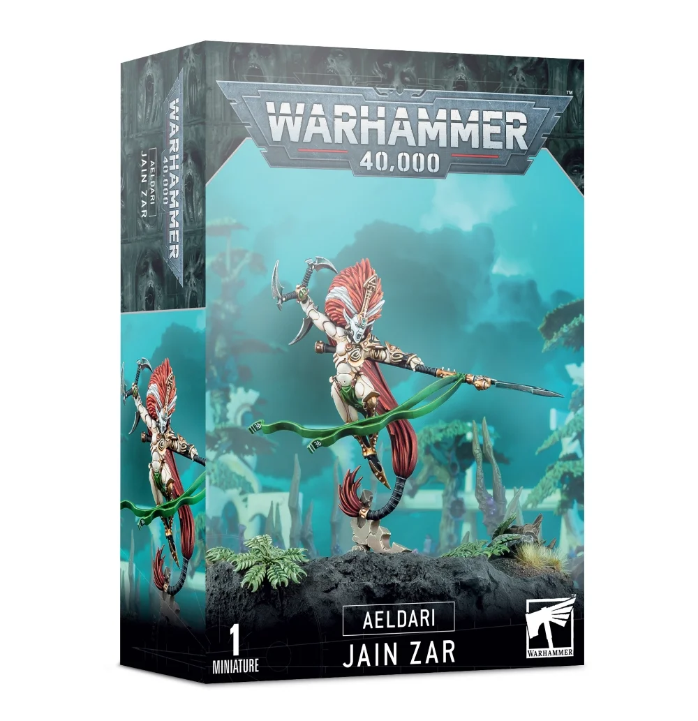 Boîte d'emballage officielle d'une figurine de personnage pour le jeu de stratégie Warhammer 40,000, présentée de trois-quarts. Le grand logo argenté de Warhammer 40,000 domine le haut de la boîte, incrusté sur une bordure supérieure gris foncé sculptée de reliefs de visages hurlants. L'illustration centrale met en valeur Jain Zar, la légendaire Seigneure Phénix des Banshees Huantes de la faction Aeldari, assemblée et peinte. Le personnage est représenté dans une posture acrobatique et aérienne ultra-dynamique, s'élançant au-dessus d'un socle rocheux gris foncé orné de petites plantes vertes. Elle arbore une armure d'os poli blanche aux détails dorés, une immense et spectaculaire chevelure rousse et blanche qui ondule vers le bas, et un masque de combat hurlant. Elle brandit sa grande lance argentée, la Mort Silencieuse, d'où flotte un long ruban vert vif, tout en armant son arme de jet incurvée de l'autre main. Le fond de l'image présente un paysage extraterrestre mystique baigné d'une lueur turquoise avec des silhouettes d'arbres exotiques et de structures de vaisseau-monde. En bas au centre, un encadré noir épuré indique les inscriptions blanches "AELDARI JAIN ZAR", flanquées de la mention "1 MINIATURE" à gauche et du logo blanc officiel de Warhammer Citadel à droite. Le rabat latéral droit, d'une teinte gris-bleu sombre, montre un aperçu vertical du personnage sous le même angle.
