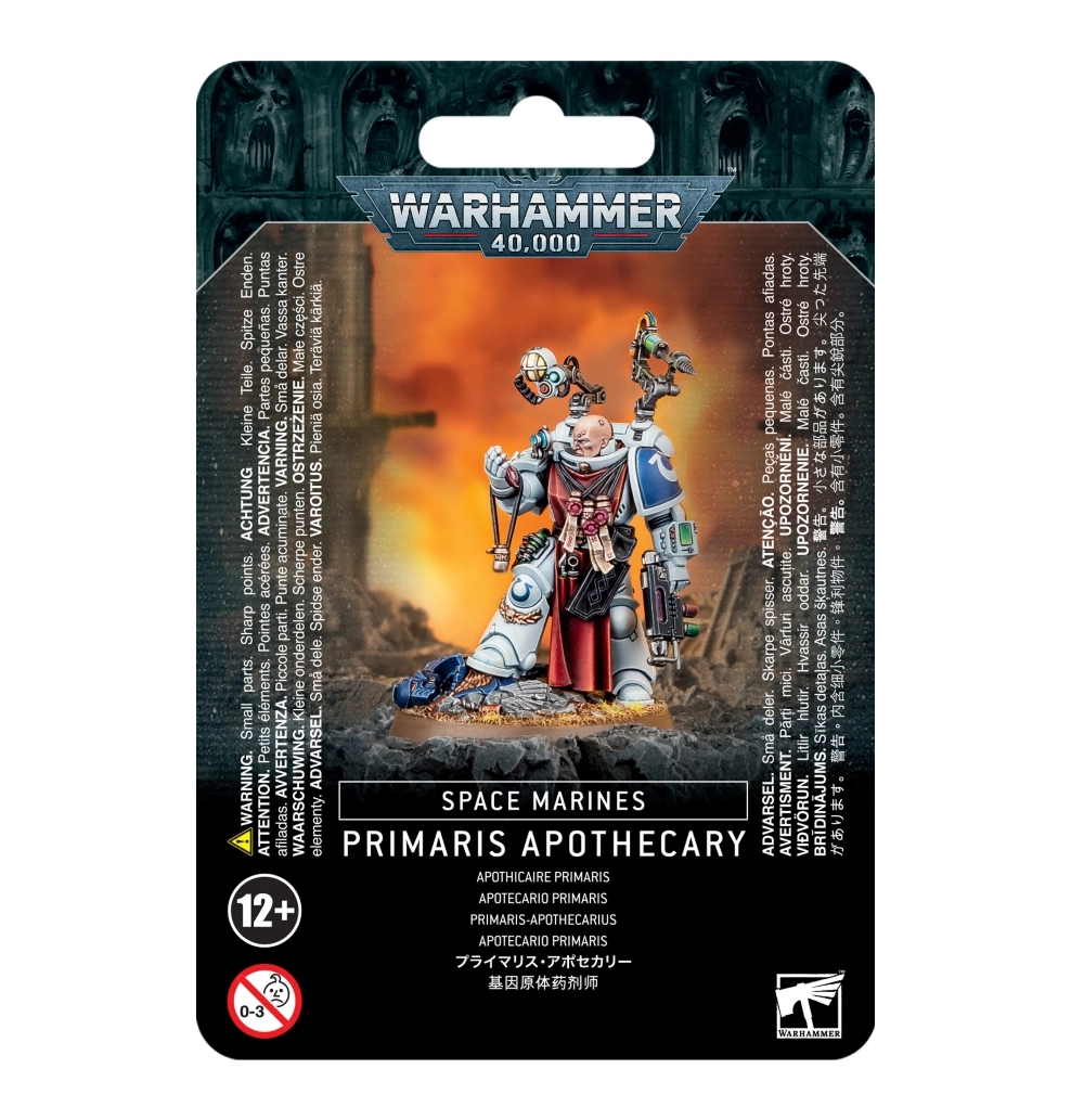 Emballage cartonné officiel de type blister à fond noir texturé pour le jeu Warhammer 40,000. Au sommet, sous l'encoche de suspension, se trouve le logo métallique bleu et gris « WARHAMMER 40,000 ». L'illustration centrale rectangulaire présente la figurine peinte d'un Apothecary Primaris appartenant au Chapitre des Ultramarines. Ce guerrier médical est revêtu d'une armure assistée lourde de couleur blanche avec une épaulière gauche bleu azur affichant le symbole de l'U blanc. Il porte un long tabard rouge suspendu à sa ceinture et un imposant paquetage dorsal équipé de bras articulés mécaniques, de scanners et de fioles médicales. Le personnage est campé sur un socle rocheux, son pied droit posé sur les débris d'une armure bleue, devant un arrière-plan de champ de bataille enveloppé par des fumées de guerre orange et jaunes. Sous l'image, un encadré noir affiche en capitales blanches les mentions « SPACE MARINES » et « PRIMARIS APOTHECARY », suivies de sa traduction en français « APOTHICAIRE PRIMARIS ». Les logos de restriction d'âge (12+) et le logo carré blanc de Games Workshop sont visibles dans les angles inférieurs.