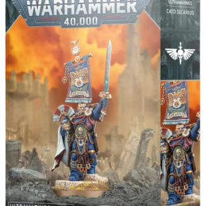 Vue en perspective de la boîte de jeu Warhammer 40,000 présentant la figurine de Cato Sicarius. Le héros est représenté avec une armure bleue ornée, une épée énergétique levée vers le ciel et une bannière de compagnie imposante dans le dos. Il est positionné sur un socle rocheux texturé au milieu d'un paysage de ruines sous un ciel orangé. Le logo "WARHAMMER 40,000" est inscrit en haut, tandis qu'en bas, sur un bandeau noir, on peut lire "ULTRAMARINES", "CATO SICARIUS" et la mention "1 CITADEL MINIATURE" à côté du logo blanc Warhammer. La tranche latérale droite affiche également le nom du personnage et le logo de la faction.