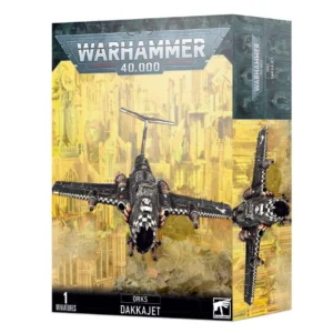 Boîte d'emballage officielle de Warhammer 40,000 au format vertical, présentant une figurine d'aéronef pour l'armée des Orks. L'illustration principale, sur un fond jaune brumeux de ruines gothiques et de cités industrielles dévastées, met en scène un avion de chasse monomoteur connu sous le nom de Dakkajet. L'appareil volant, peint en métal noir usé, possède des ailes droites ornées d'un motif à damiers noirs et blancs sur les bords d'attaque et d'un insigne de crâne Ork blanc sur le dessus du fuselage. Il dispose d'une large entrée d'air frontale béante évoquant une mâchoire agressive et est lourdement armé de plusieurs paires de gros canons mitrailleurs d'ailes. Le logo officiel argenté "WARHAMMER 40,000" domine le haut de la boîte. La bande noire inférieure affiche les mentions textuelles "1 MINIATURE", "ORKS DAKKAJET" au centre, ainsi que le logo blanc de Games Workshop dans le coin inférieur droit.