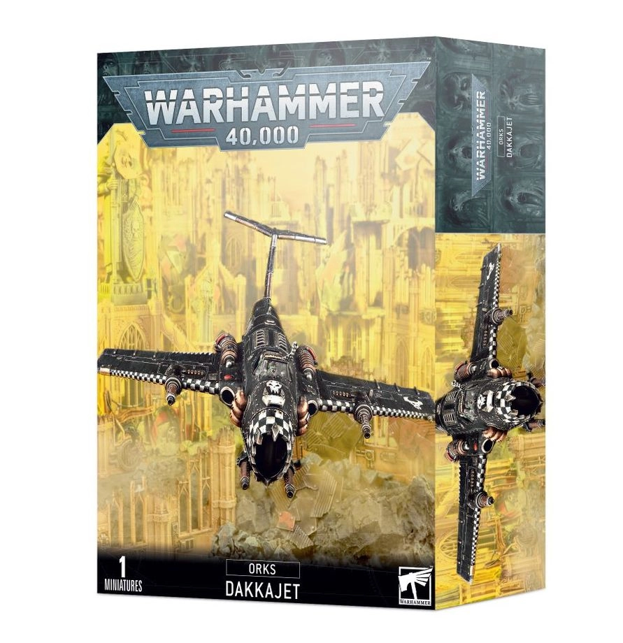 Boîte d'emballage officielle de Warhammer 40,000 au format vertical, présentant une figurine d'aéronef pour l'armée des Orks. L'illustration principale, sur un fond jaune brumeux de ruines gothiques et de cités industrielles dévastées, met en scène un avion de chasse monomoteur connu sous le nom de Dakkajet. L'appareil volant, peint en métal noir usé, possède des ailes droites ornées d'un motif à damiers noirs et blancs sur les bords d'attaque et d'un insigne de crâne Ork blanc sur le dessus du fuselage. Il dispose d'une large entrée d'air frontale béante évoquant une mâchoire agressive et est lourdement armé de plusieurs paires de gros canons mitrailleurs d'ailes. Le logo officiel argenté "WARHAMMER 40,000" domine le haut de la boîte. La bande noire inférieure affiche les mentions textuelles "1 MINIATURE", "ORKS DAKKAJET" au centre, ainsi que le logo blanc de Games Workshop dans le coin inférieur droit.
