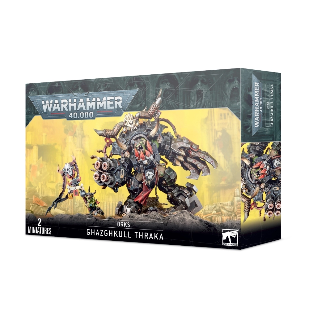Boîte d'emballage officielle de Warhammer 40,000 présentant un kit de figurines de personnages majeurs pour l'armée des Orks. L'illustration principale, sur un fond jaune brumeux de cité industrielle dévastée, met en scène le gigantesque Seigneur de Guerre connu sous le nom de Ghazghkull Thraka. Ce monstre à la peau verte, hurlant de rage, porte une immense méga-armure cybernétique en métal noir et plaques boulonnées. Il est équipé d'une terrible pince énergétique à quatre lames tranchantes sur son bras gauche et d'un quadruple canon automatique massif à sa main droite. Un grand crâne à cornes surmonte son armure. À sa droite se tient Makari, un petit Grot à la peau verte brandissant une grande icône mécanique ornée d'un crâne Ork stylisé. Le logo officiel argenté "WARHAMMER 40,000" domine le haut de la boîte. La bande noire inférieure affiche les mentions textuelles "2 MINIATURES", "ORKS GHAZGHKULL THRAKA" au centre, ainsi que le logo de Games Workshop dans le coin inférieur droit.
