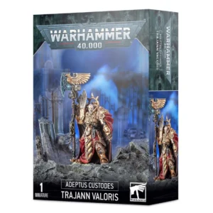 Boîte d'emballage rectangulaire de la figurine Captain-General Trajann Valoris pour le jeu Warhammer 40,000. Le design de la boîte affiche en haut le grand logo gris métallique de « Warhammer 40,000 ». Au centre, une illustration montre la figurine assemblée et peinte du personnage, un guerrier en armure dorée ornée, portant une longue cape rouge et brandissant une imposante hache de gardien surmontée d'un aigle sculpté. Il se tient debout sur un sol rocheux et gris, devant un arrière-plan flou représentant des ruines gothiques dans une ambiance nocturne bleutée. Le bas de la boîte comporte les inscriptions en blanc « 1 Miniature », « Adeptus Custodes » et le nom du personnage « Trajann Valoris », à côté du logo carré noir et blanc de Warhammer. Le côté de la boîte montre également un aperçu vertical de la figurine.