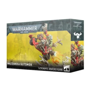 Boîte de produit officielle Warhammer 40,000 présentant le kit de la figurine de Wazdakka Gutsmek pour la faction des Orks. L'illustration principale montre un puissant Ork à la peau verte, hurlant de rage, aux commandes d'une imposante moto personnalisée rouge et grise qui cabre de manière spectaculaire sur des rochers, propulsée par des flammes d'échappement sculptées. La moto est équipée d'une arme à tir rapide massive à l'avant et de crânes décoratifs à l'arrière. L'arrière-plan de l'emballage affiche un décor de ruines industrielles dans des teintes jaune-vert brumeuses. Le logo blanc "Warhammer 40,000" est visible en haut à gauche, le nom du personnage est inscrit en blanc en bas à gauche, et le logo Citadel miniature apparaît en bas à droite.