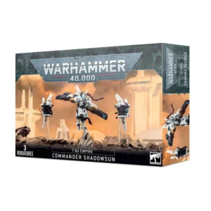 Boîte de produit officielle Warhammer 40,000 présentant le kit de figurines T'AU EMPIRE: COMMANDANTE SHADOWSUN. L'illustration centrale montre la figurine de la Commandante Shadowsun en armure de combat blanche et grise XV22, progressant sur un décor rocheux. Elle possède une longue chevelure rousse tressée et brandit deux éclateurs à fusion. Elle est flanquée de deux drones tactiques montés sur des tiges transparentes. Le fond de l'image affiche un paysage de science-fiction baigné dans une lumière crépusculaire orangée avec des bâtiments futuristes de l'Empire T'au. Le logo imposant argenté "Warhammer 40,000" domine le haut de la boîte, tandis que l'inscription "T'AU EMPIRE COMMANDER SHADOWSUN" et la mention "3 MINIATURES" apparaissent en blanc au bas du packaging.