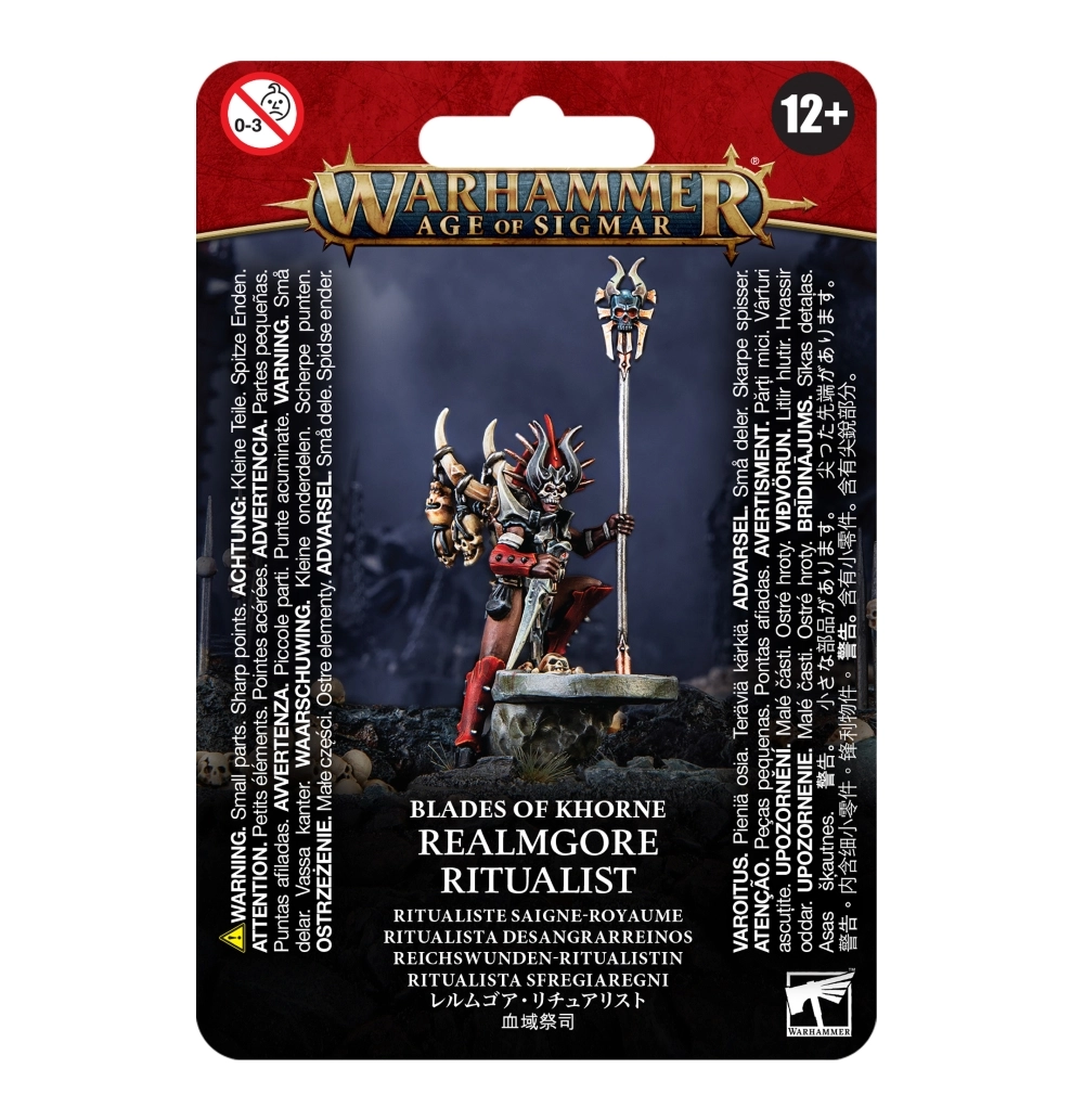 Visuel de l'emballage sous blister de la figurine du Ritualiste Saigne-royaume pour la faction Blades of Khorne dans Warhammer Age of Sigmar. La carte de conditionnement présente en haut une bannière rouge bordeaux avec le logo officiel Warhammer Age of Sigmar en lettres métalliques dorées. Au centre, la figurine peinte met en scène un prêtre menaçant arborant un masque de crâne surmonté d'une coiffe à piques rouges et noires. Vêtu d'une armure rouge sombre avec des crânes suspendus à ses épaulettes, le personnage tient une dague rituelle et s'appuie sur un grand bâton de pouvoir surmonté d'un crâne cornu et de l'icône de Khorne. Le bas de l'emballage indique BLADES OF KHORNE REALMGORE RITUALIST suivi du nom traduit RITUALISTE SAIGNE-ROYAUME en lettres blanches, avec le logo carré blanc Citadel Warhammer dans le coin inférieur droit.