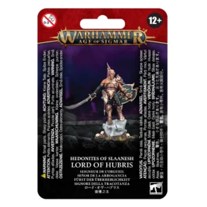 Photo de présentation sur fond blanc du blister de packaging de la figurine du Seigneur de l'Orgueil. L'emballage au fond rouge texturé est surmonté du logo officiel "WARHAMMER AGE OF SIGMAR" en lettres dorées et bleues. L'illustration centrale, sur un fond violet nocturne avec des vestiges de ruines, présente un guerrier humanoïde torses nus au physique sculpté. Il est vêtu d'une armure dorée et sculptée sur la jambe et l'épaule gauche, tenant une épée courbe dans sa main droite et un bouclier orné dans la gauche. Il se tient fièrement sur une tête de statue brisée entourée de crânes. En bas, le texte indique "HEDONITES OF SLAANESH LORD OF HUBRIS" suivi de la traduction en français "SEIGNEUR DE L'ORGUEIL". Les pictogrammes de sécurité "0-3" et "12+" encadrent la partie supérieure, tandis que le logo officiel "WARHAMMER" figure dans le coin inférieur droit.