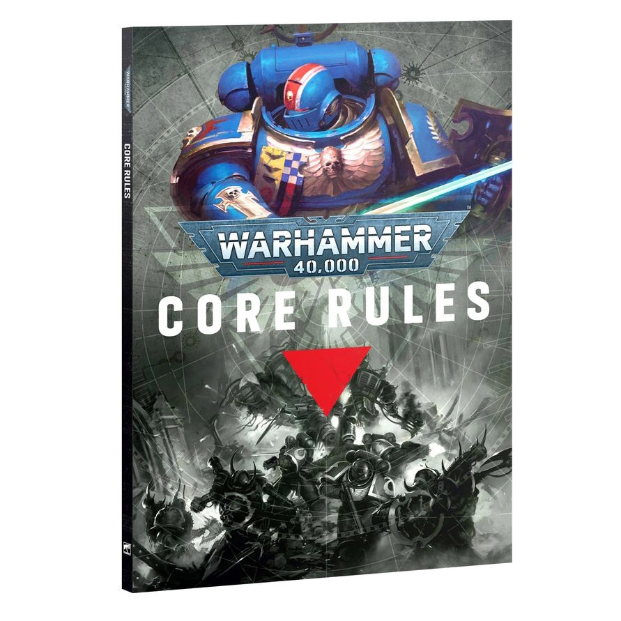 A product shot showing the front cover and thin black spine of the Warhammer 40,000 Core Rules (Anglais) book, viewed from a three-quarters angle against a white background. The upper section features a vibrant illustration of a blue-armored Ultramarines Space Marine with golden trim and a red and white striped helmet, wielding a glowing blue power sword. In the center, the iconic blue and silver Warhammer 40,000 logo is positioned above the bold white title text 'CORE RULES', which is underscored by a bright red inverted triangle. The lower half of the cover displays dramatic black and white artwork depicting grimdark soldiers engaged in fierce combat amidst ruined gothic architecture.