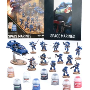 Contenu complet du kit de démarrage Warhammer 40,000 : Commencer avec les Space Marines disposé proprement sur un fond blanc. En arrière-plan à gauche, la boîte d'emballage affiche les textes "COMMENCEZ ICI" et "COMMENCER AVEC LES SPACE MARINES" sous le logo officiel Warhammer 40,000, illustrant une scène de bataille spatiale. À droite se trouve un livret de découverte noir arborant le même logo et le gros plan d'un soldat en armure énergétique bleue. Le logo Warhammer Community est visible en haut à droite de l'image. Au centre, douze figurines de Space Marines peintes aux couleurs des Ultramarines (bleu brillant, touches d'or et de blanc) sont prêtes au combat. On y distingue des troupes d'infanterie, des guerriers équipés de réacteurs dorsaux, des leaders armés d'épées et de boucliers, ainsi qu'un véhicule d'assaut léger antigravité surélevé sur un socle transparent. Au premier plan, onze pots de peinture Citadel Colour de 12ml sont alignés. Leurs étiquettes affichent clairement les noms des teintes : Retributor Armour, Corax White, Abaddon Black, Macragge Blue, Leadbelcher, Mournfang Brown, Mephiston Red, ainsi que les pots techniques Nuln Oil, Astrogranite, Dawnstone et Wraithbone. Un pinceau fin Citadel Starter gris est posé horizontalement devant les pots de peinture.