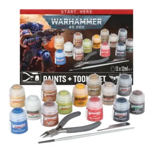 Une vue d'ensemble du contenu du produit Warhammer 40,000: Set Peintures + Outils, exposé de face sur un fond blanc uni. À l'arrière-plan, la boîte d'emballage affiche sur sa partie supérieure un bandeau rouge avec l'inscription « START HERE », surplombant le logo officiel gris et bleu « WARHAMMER 40,000 ». La gauche de la boîte est illustrée par un Space Marine Ultramarine en armure bleue brandissant son bolter. La section inférieure noire de la boîte montre le titre « PAINTS + TOOLS SET », le logo blanc de Games Workshop, l'emblème de l'Aquila impériale, la mention « 13 x 12ml e », ainsi que des icônes blanches détaillant les quantités incluses : une pince, un grattoir, un pinceau et treize pots. Au premier plan, tous les outils et pots de peinture Citadel Colour sont disposés de manière bien visible. On y retrouve une pince coupante aux poignées grises, un outil d'ébarbage métallique, un pinceau à manche gris portant l'inscription « WARHAMMER STARTER BRUSH », ainsi que treize pots de peinture affichant clairement leurs teintes sur les étiquettes : Macragge Blue, Zandri Dust, Corax White, Retributor Armour, Mournfang Brown, Orruk Flesh, Averland Sunset, Mephiston Red, Armageddon Dust, Rakarth Flesh, Leadbelcher, Abaddon Black et Agrax Earthshade.