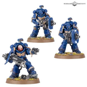 Photo de présentation sur fond blanc de trois figurines peintes pour l'Escouade Eradicator avec Bolters Lourds des Space Marines. Les guerriers portent l'armure lourde Gravis aux couleurs bleues et dorées du chapitre des Ultramarines. Au premier plan à gauche, le sergent à tête nue porte un masque respiratoire rouge, tient un imposant bolter lourd sous le bras et braque un pistolet pistolet bolter de la main gauche. Derrière lui, les deux autres Space Marines portent des casques bleus aux lentilles rouges et sont en position de tir, épaulant des bolters lourds massifs dotés de boucliers de protection et de viseurs optiques dorsaux. Les figurines reposent sur des socles décorés de terre, de rochers et de brins d'herbe sèche. Le logo « WARHAMMER COMMUNITY » figure en haut à droite.